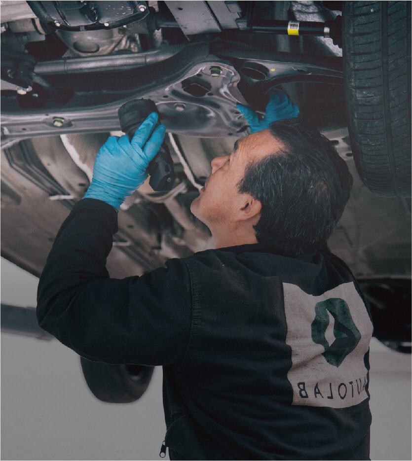Mecánico de Autolab inspecciona un carro desde abajo