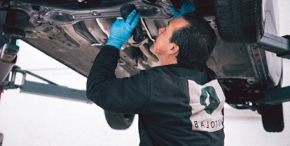 Mecánico de Autolab inspecciona un carro desde abajo