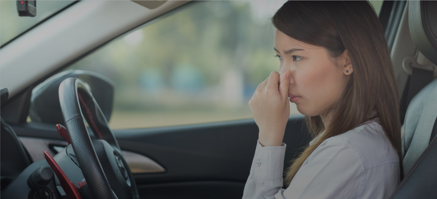 Mujer sentada en un carro y se tapa la nariz porque huele mal.